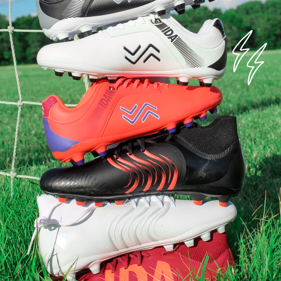 IDA women's specific football boots stacked on top of each other on a grass pitch