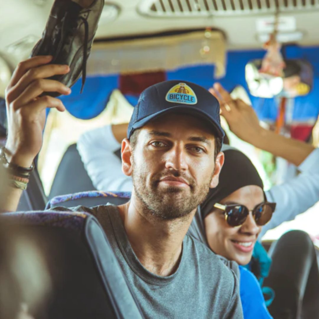 IDA Sports co-founder, Ben Sandhu, holds up a black leather women's soccer cleat prototype while on a bus going to a women's soccer game.