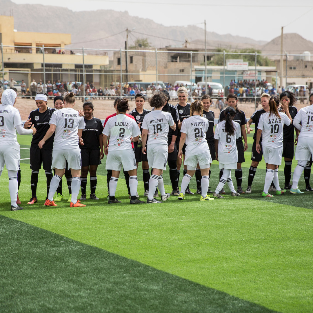Women's soccer players from Equal Playing Field shake hands in a line up after a soccer game.